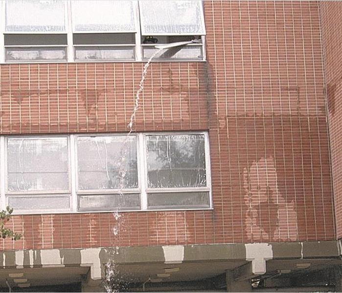 Water is shown being pumped out of a flooded commercial building.